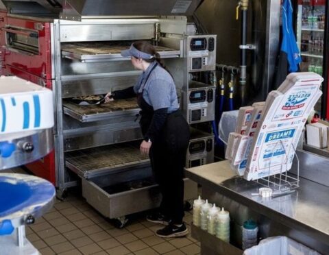 A Domino's worker maintaining the oven